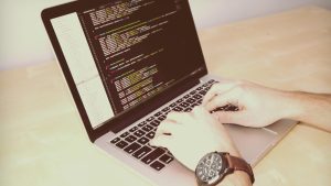 Développeur tapant du code sur un ordinateur portable, dans un bureau lumineux